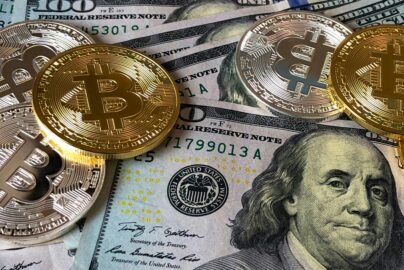 A close-up photo depicting Bitcoin coins on top of US dollar bills, symbolizing finance and cryptocurrency.