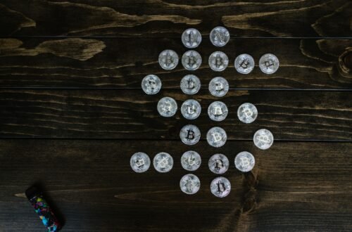 Flat lay of Bitcoin coins arranged in a shape on a wooden surface representing digital currency.