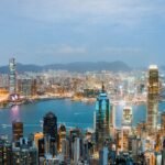 Explore the breathtaking skyline of Hong Kong at dusk, highlighting vibrant lights and Victoria Harbor.